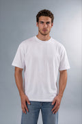 A man wearing a plain white short-sleeve crewneck t-shirt and blue jeans, standing against a neutral gray studio background.
